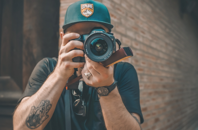 Image of a man holding a large camera up to his face, and looking through the lense