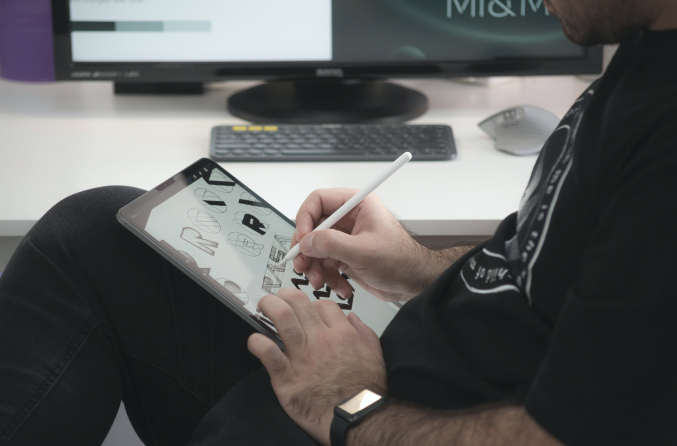 Close up image of person sitting a desk and drawing on their iPad